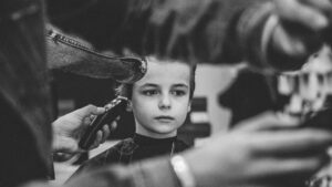 Jongen zit rustig bij de kapper, ervaart zelfredzaamheid door zelfstandig keuzes te maken.
